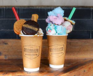 2 tall glasses of Hot chocolate topped with cookies and treats from Bombobar